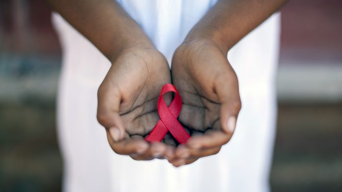 Child's hands holding an HIV awareness ribbon, Cape Town, South Africa